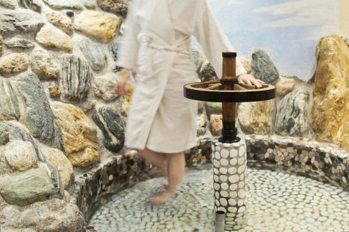 a woman in a white suit standing next to a fountain at Landhotel Untermüllnergut in Dorfgastein