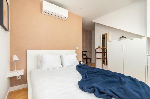 a bedroom with a white bed with a blue blanket on it at Belem Design Apartments by Homing in Lisbon