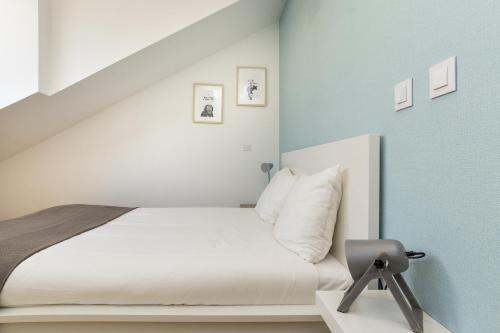 a bedroom with a white bed and a chair at Belem Design Apartments by Homing in Lisbon