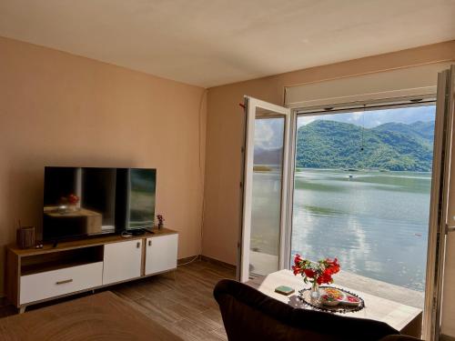 a living room with a tv and a large window at Lakeside Harmony Apartment in Golubovci