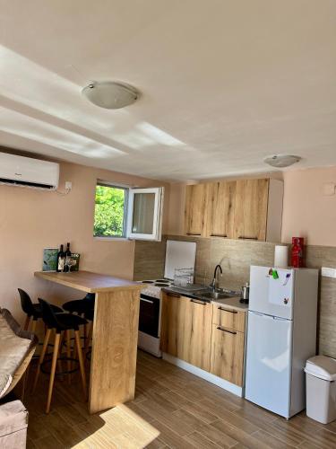 a kitchen with wooden cabinets and a white refrigerator at Lakeside Harmony Apartment in Golubovci