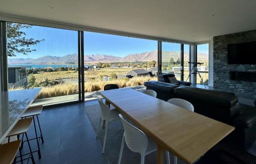 a living room with a table and a large window at Luxury Lakeview Apartment - Lake Tekapo in Lake Tekapo