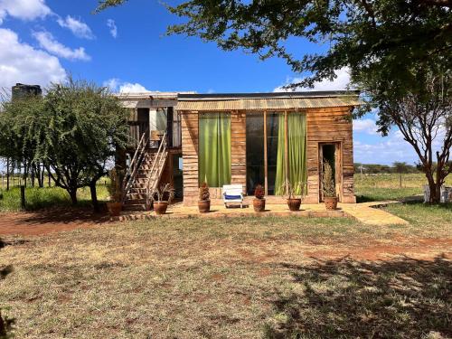 una pequeña casa de madera con cortinas verdes. en Kilimanjaro view cabin-Amboseli en Oloitokitok 
