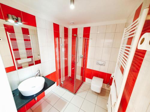 a red and white bathroom with a shower and a sink at Penzion Patriot in Výprachtice