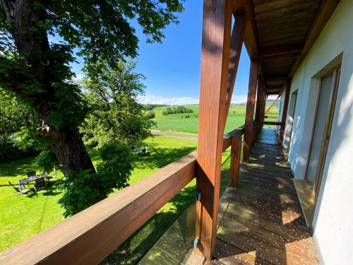 a wooden porch of a house with a tree at Penzion Patriot in Výprachtice