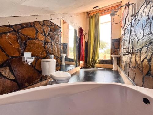 Oloitokitok 的住宿－Kilimanjaro view cabin-Amboseli，一间带大浴缸和石墙的浴室