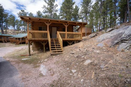 a wooden cabin on a hill with a porch at Rock Crest Lodge & Cabins in Custer