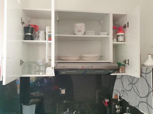 a kitchen with white cabinets with dishes in it at Appartement Cosy Disponible in Kenitra