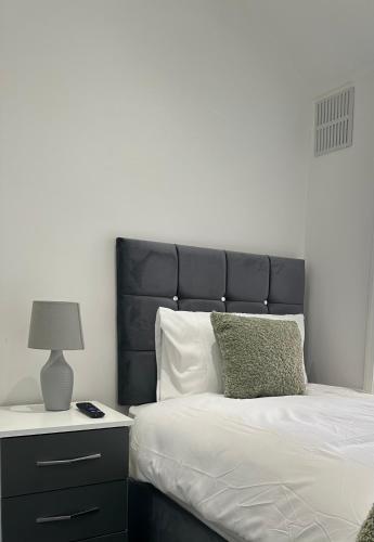 a bed with a black headboard next to a night stand at Marvellous Single Room in Middlesbrough