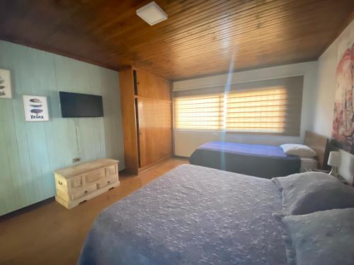 um quarto com duas camas e uma televisão em Habitaciones Mar Azul em El Quisco