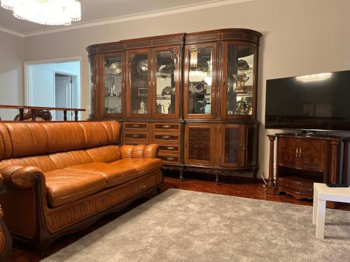 a living room with a brown leather couch and a television at Olympic Apartment in Braga