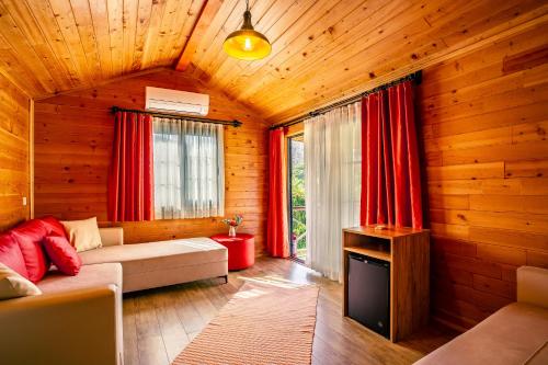 a living room with a couch and red curtains at Izgen Bungalows in Cıralı