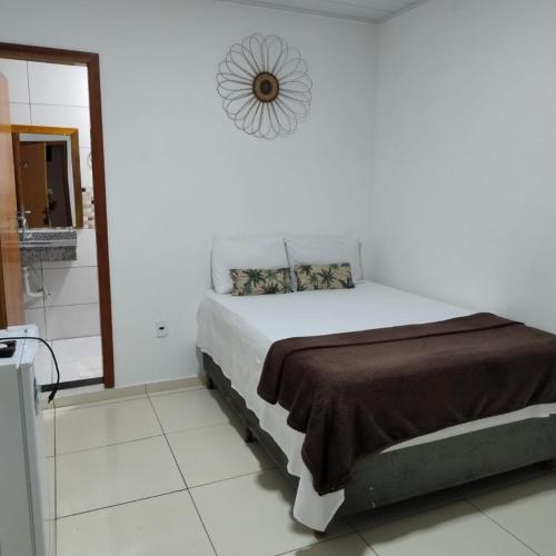 a white bedroom with a bed and a clock on the wall at Pousada Vila Jesuita in Cairu
