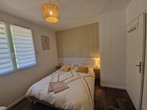 a bedroom with a bed with white sheets and a window at Le Nid Cabailla in Coimères