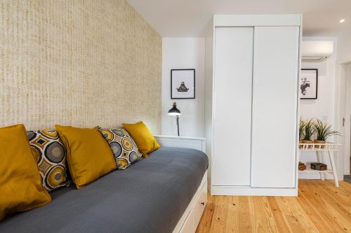 a living room with a couch with yellow pillows at Design and bright studios near Pastéis de Belém in Lisbon