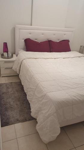 une chambre avec un grand lit blanc avec des oreillers rouges dans l'établissement Bienvenue à Carcassonne, à Carcassonne