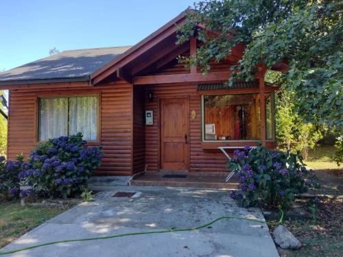 a wooden house with a yard with purple flowers at Cabanas Rimari in Pucón