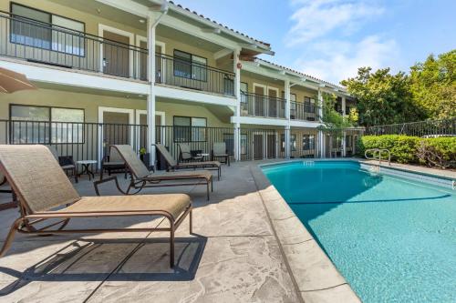 a patio with chairs and a swimming pool in front of a building at Best Western Plus Inn Scotts Valley in Scotts Valley