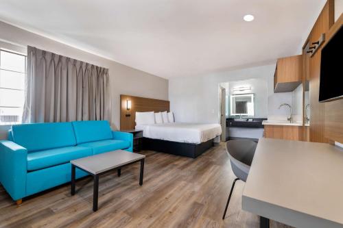 Habitación de hotel con sofá azul y cama en Motel 6-Santa Ana, CA en Santa Ana