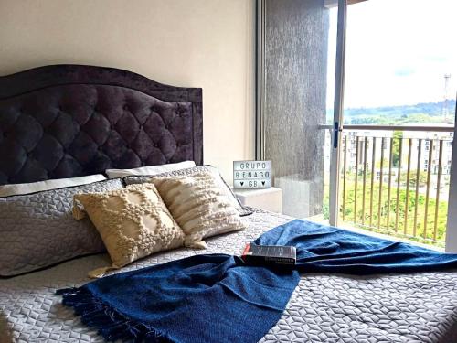 - un lit avec une couverture bleue et une fenêtre dans l'établissement Apto Amoblado Armenia - Espectacular Vista al Horizonte, à Armenia