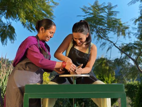 two women are sitting on a green bench at Rakkh Resort, a member of Radisson Individuals Retreats in Pālampur