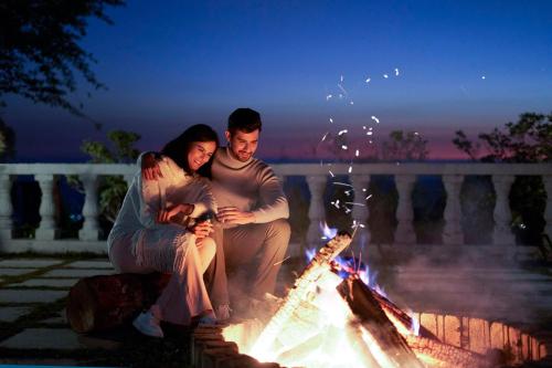 a man and woman sitting next to a fire pit at Rakkh Resort, a member of Radisson Individuals Retreats in Pālampur