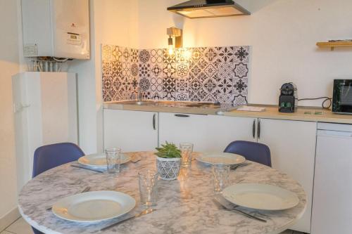 une cuisine avec une table avec des assiettes et des verres dessus dans l'établissement Cosy et Calme avec parking, à Villeurbanne