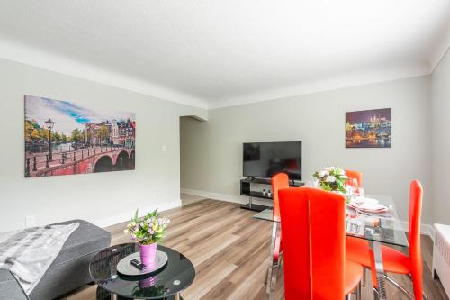a living room with a dining room table with orange chairs at Modern Apartment - Corktown Hamilton in Hamilton