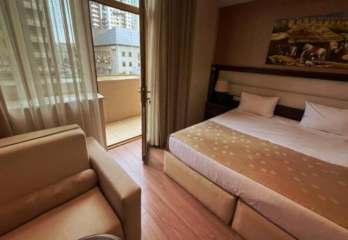 um quarto com uma cama, um sofá e uma janela em Smith Hotel Baku em Baku