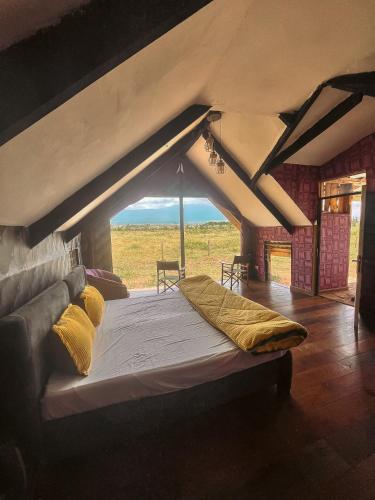a large bed in a room with an attic at Amboseli Glass Cabin in Kimana
