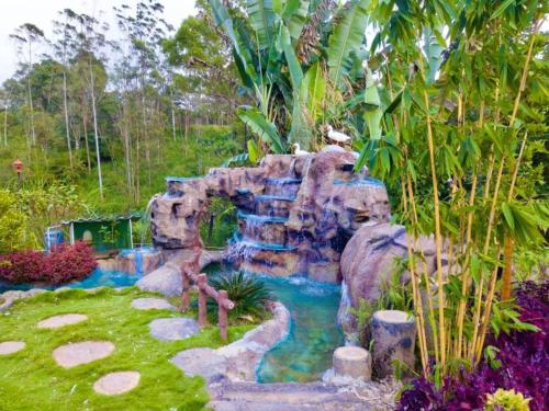 a waterfall in the middle of a garden at Mount Edge Riverside Hotel in Bandarawela