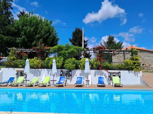 a group of chairs and umbrellas next to a swimming pool at Alqueiturismo - Casas de Campo in Guarda