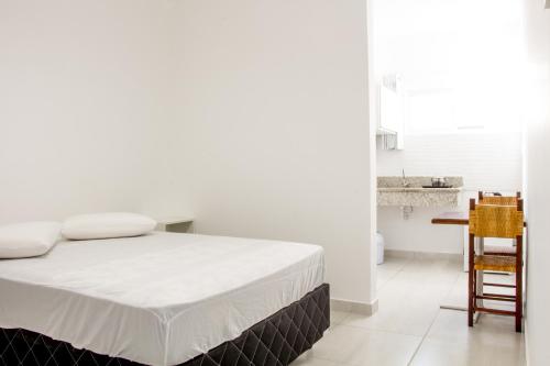 a bedroom with a bed and a table and a chair at Canto das Ondas Apart Studios in São Francisco do Sul