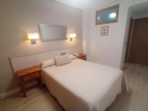 Un pequeño dormitorio con una cama blanca y una ventana en Hostal Atienzar en Albacete