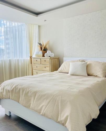 1 cama blanca en un dormitorio con ventana en Suite UIO, en Quito