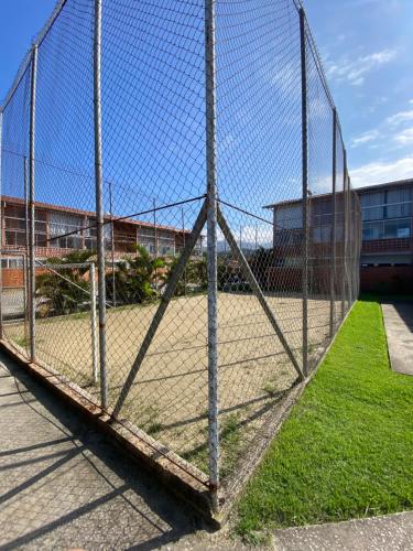 a tennis court behind a chain link fence at Apartamento em Ubatuba - Condomínio Ville II - 300 metros da Praia do Sapê - Maranduba in Ubatuba