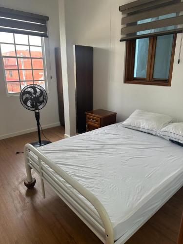 a bedroom with a white bed and a window at Alice's Abode in Port-of-Spain