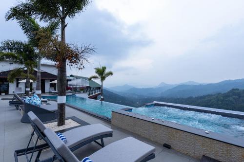 a swimming pool with chairs and a view of the mountains at The Panoramic Getaway in Munnar