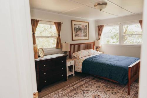 a bedroom with a bed and a dresser and two windows at Bay View Casita in Olympia