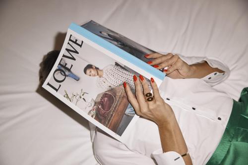 una mujer acostada en la cama leyendo una revista en QT Singapore en Singapur