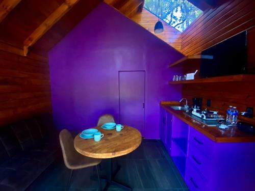 Habitación púrpura con mesa y lavamanos en Casa Alfeñique, en Villa del Carbón