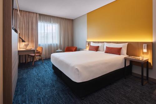 a hotel room with a large bed and a desk at Rydges Sydney Airport Hotel in Sydney