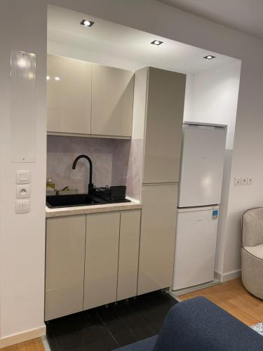 une cuisine avec des armoires blanches, un évier et un réfrigérateur dans l'établissement Chevilly Cosy, à Chevilly-Larue