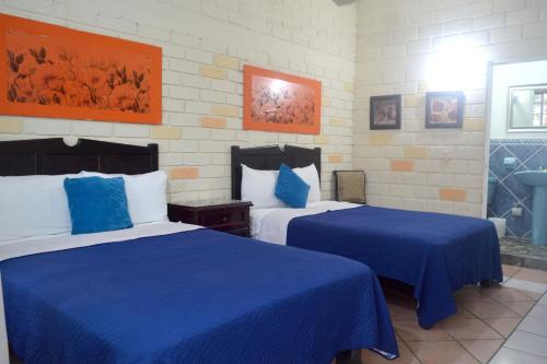 una camera d'albergo con due letti con lenzuola blu di Estancia Las Flores a San Blas