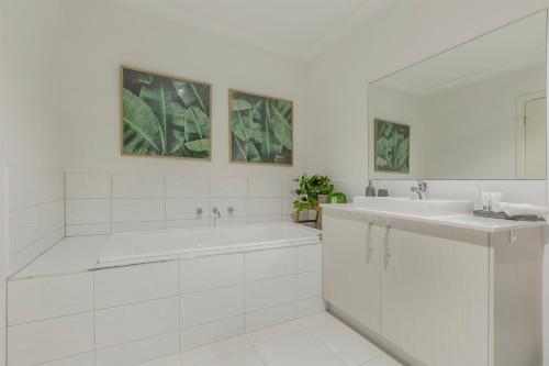 a white bathroom with a tub and a sink at VAQUAY Contempo In Flemington in Melbourne