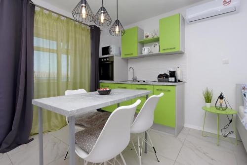 a kitchen with green cabinets and a table and chairs at Apartments by the sea Senj - 22576 in Senj