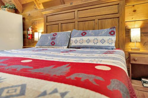 a bed with a red and blue comforter and pillows at Cozy Cabin! Hot Tub, King Bed, Fireplace, & Pool in Gatlinburg