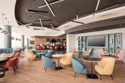 a waiting room with tables and chairs and a flat screen tv at Holiday Inn Norwich City by IHG in Norwich