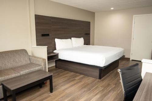 a bedroom with a bed and a couch and a chair at Americas Best Value Inn Harlingen in Harlingen