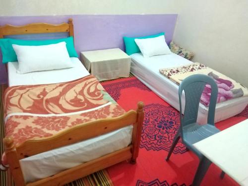 um pequeno quarto com 2 camas e uma cadeira em Aziz House 1 em Tan-Tan